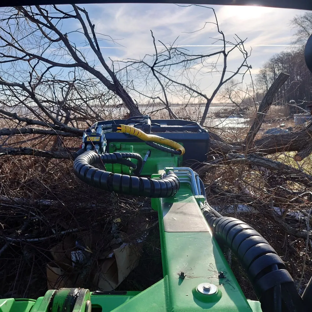 Vy från en Avant där gripen lyfter en stor hög med ris och grenar